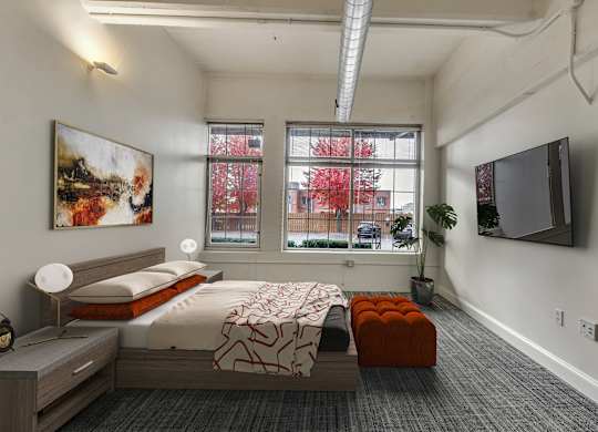 Modern bedroom with platform bed and wall mounted tv at The Lofts at Elk Terminal Apartments, New York