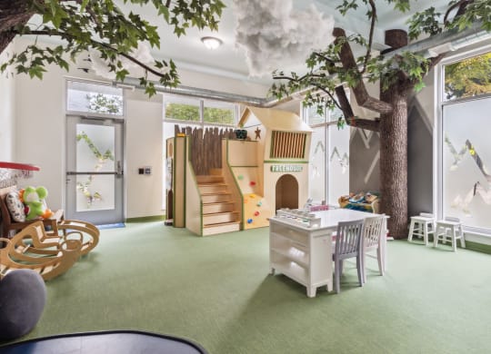 a playroom with a tree in the center of a room with a playhouse at Bakery Living, Pittsburgh, PA