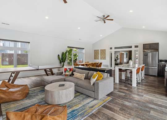 A modern living room with a grey couch and a round ottoman. at Highland Village, Ross Township, Pittsburgh, PA 15229