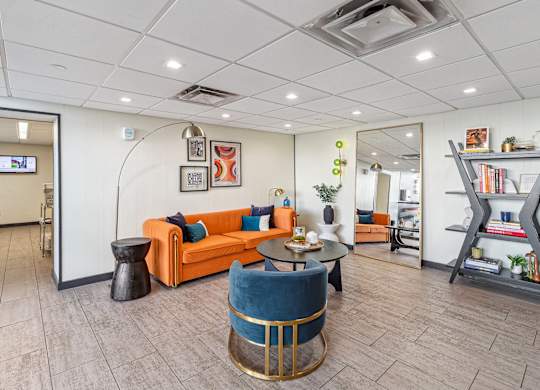 A living room with a blue chair and orange couch at Walnut Towers at Frick Park, Pennsylvania