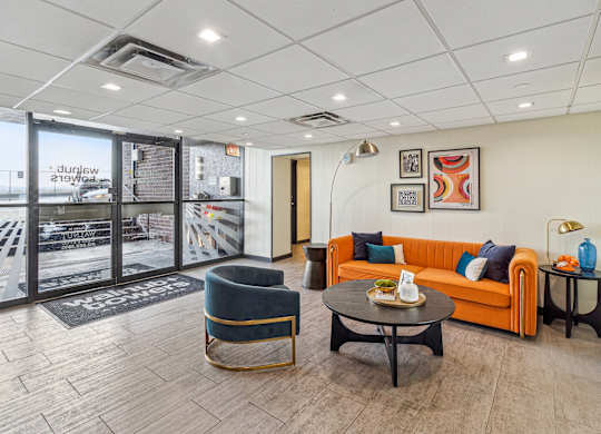 A living room with a sofa, armchair, and coffee tables at Walnut Towers at Frick Park, Pittsburgh