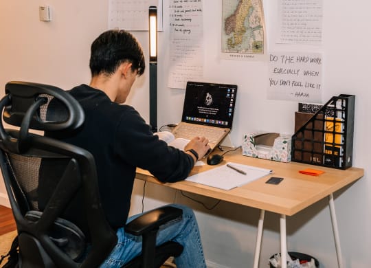 a man sitting at a desk with a laptop at University Commons Apartments, Oakland, Pittsburgh