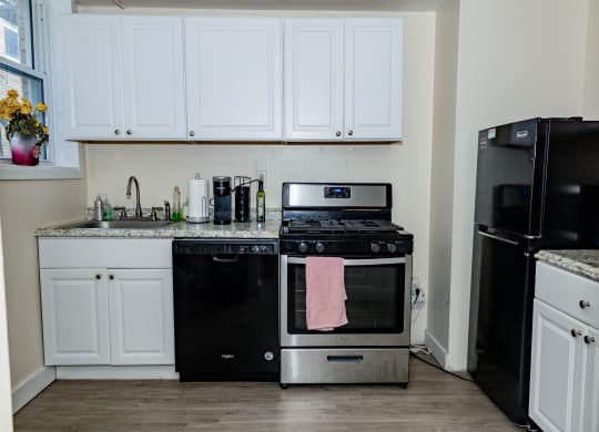 a kitchen with white cabinets and black appliances at University Commons Apartments, Oakland, Pittsburgh