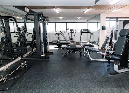A gym with a variety of equipment including a leg press machine, a chest press machine, and a rowing machine at Walnut Towers at Frick Park, Pittsburgh, Pennsylvania