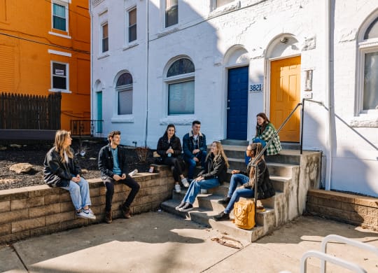 a group of people sitting on the steps of a building at University Commons Apartments, Oakland, Pittsburgh