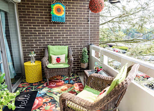 A patio with a chair and a table with a yellow tablecloth. at Walnut Crossings, Monroeville, PA, 15146