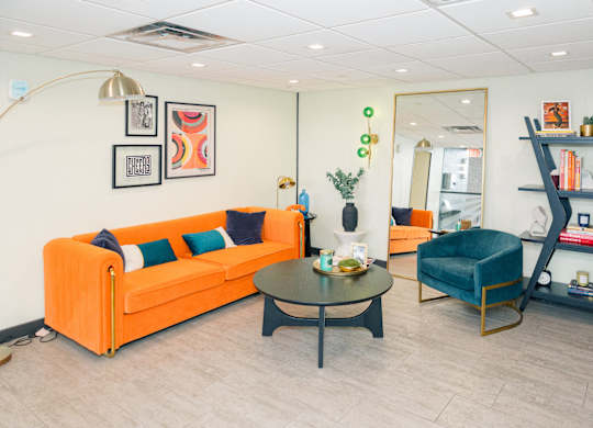 A living room with a sofa, armchair, and coffee table at Walnut Towers at Frick Park, Pittsburgh