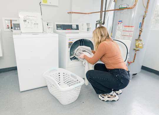 A woman is doing laundry in a laundromat at Walnut Towers at Frick Park, Pennsylvania 15217