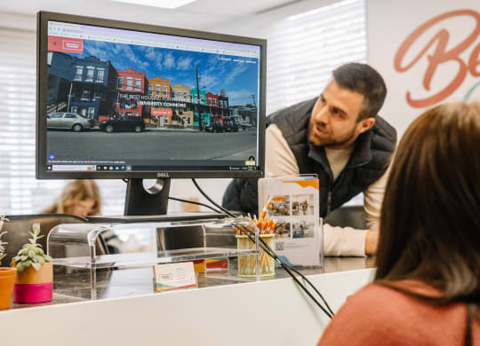 a man and a woman sitting at a desk in front of a computer monitor at University Commons Apartments, Oakland, Pittsburgh
