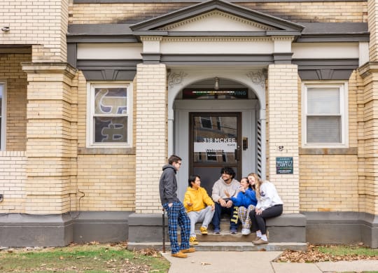 a group of people sitting on the steps of a building at University Commons Apartments, Oakland, Pittsburgh