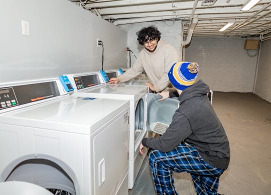 two people installing a washing machine in a laundromat at University Commons Apartments, Oakland, Pittsburgh