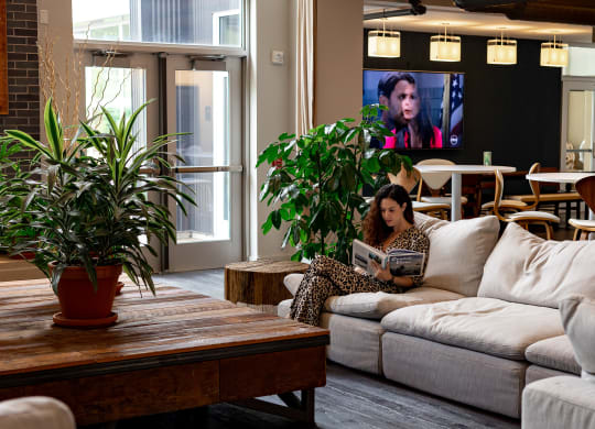 a woman sitting on a couch in a living room with a tv in the background at Bakery Living in Pittsburgh, PA 15206