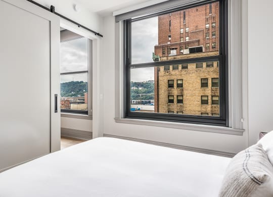 a bedroom with a large window and a white bed at The Commonwealth Building, Pittsburgh, Pennsylvania