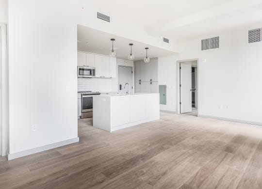 an empty living room and kitchen with white walls and wood floors at The Commonwealth Building, Pittsburgh, Pennsylvania