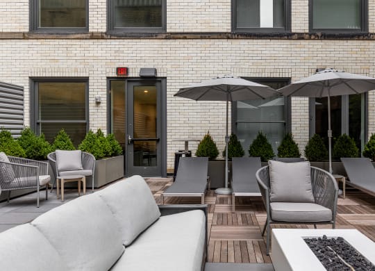 a patio with couches chairs and umbrellas in front of a brick building at The Commonwealth Building, Pittsburgh, 15222