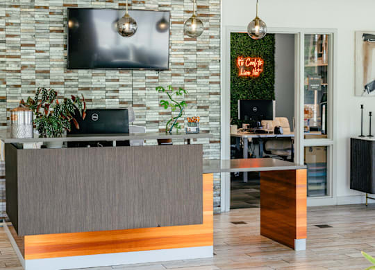 A reception desk with a plant on it in front of a stone wall.