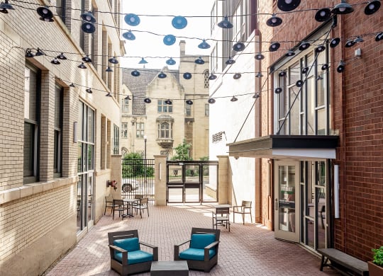 a courtyard with blue chairs and a red brick building in the background at Walnut on Highland, Pittsburgh, PA