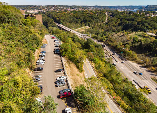 A parking lot with cars is situated on a hillside at Walnut Towers at Frick Park, Pittsburgh, PA