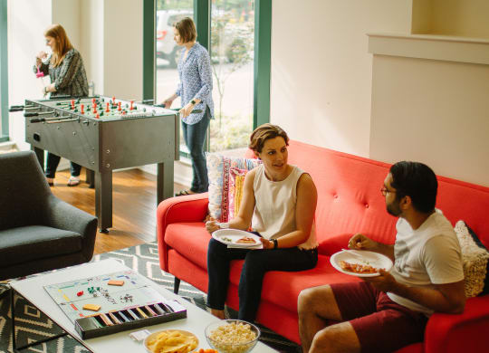 a group of people sitting in a living room next to a foosball table