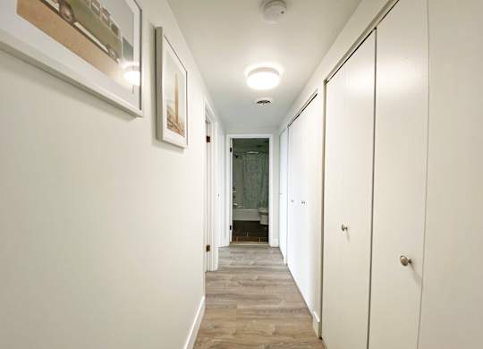 A long hallway with white walls and wood flooring at Walnut Towers at Frick Park, Pittsburgh, Pennsylvania