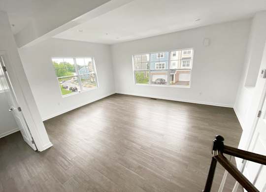 A spacious room with a wooden floor and a view of a parking lot through the windows. at Highland Village, Ross Township, Pittsburgh, PA 15229