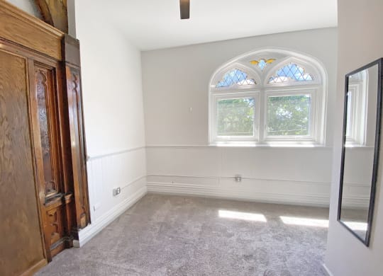 Carpeted Living Space with Unique Window at University Commons Apartments, Oakland, PA
