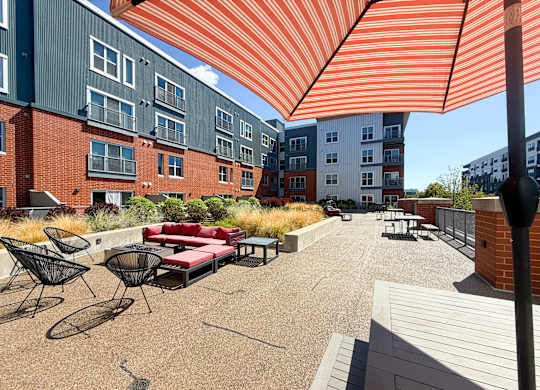 A patio with a red couch and chairs under a striped orange and white awning. Hot Metal Flats apartments, Southside Pittsburgh, PA
