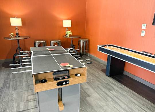 A ping pong table is in the middle of a room with orange walls.
