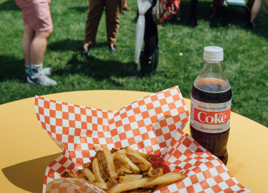 a table with a basket of food and a bottle of coke on it at University Commons Apartments, Oakland, Pittsburgh