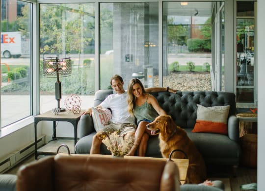 a man and a woman sitting on a couch with a dog