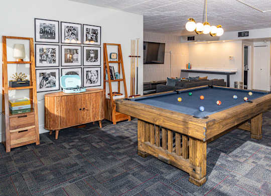 A pool table in a room with a wooden cabinet and a wall of framed pictures at Walnut Towers at Frick Park, Pittsburgh, 15217