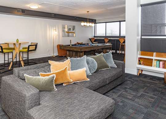 A grey couch with orange and green pillows in a room at Walnut Towers at Frick Park, Pittsburgh, PA