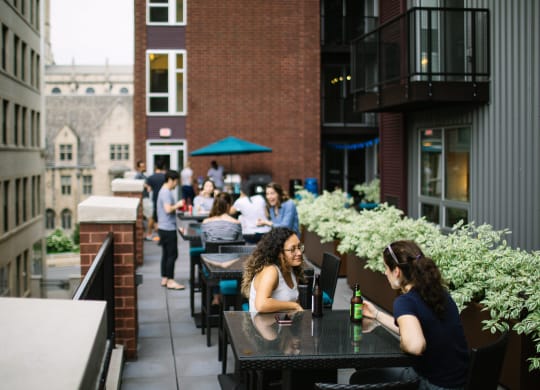 people sitting at tables on a patio in front of a brick building