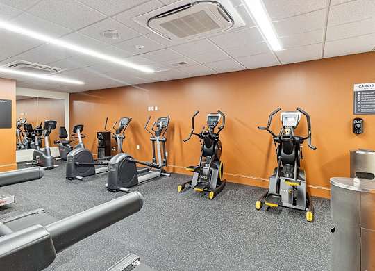 A gym with orange walls and a variety of exercise equipment. at The Washington at Chatham, Pennsylvania, 15219
