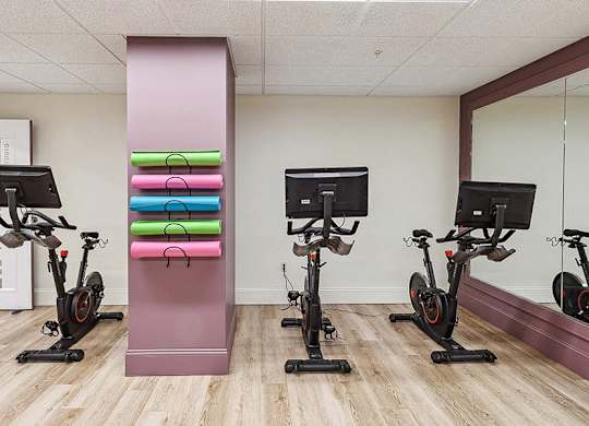 A gym with exercise bikes and a mirror. at The Washington at Chatham, Pennsylvania, 15219