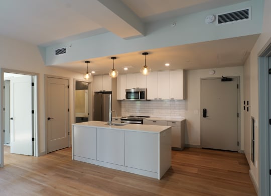 a kitchen with white cabinets and a white island in the middle at The Commonwealth Building, Pittsburgh, 15222