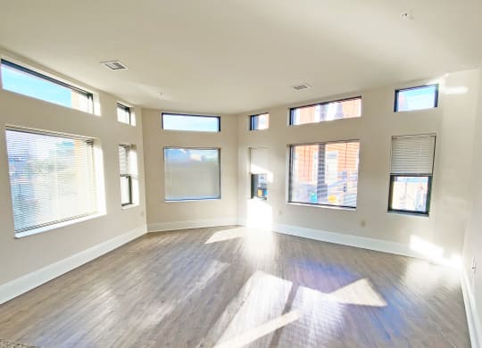 an empty living room with windows and hardwood floors