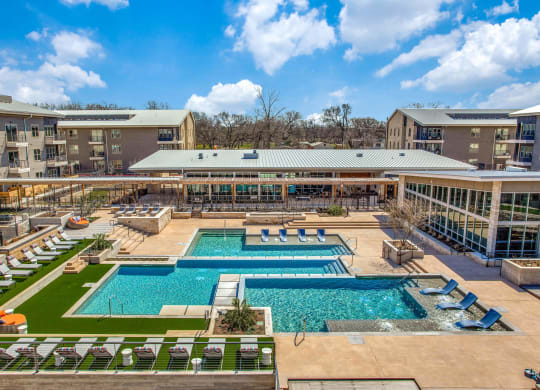 an aerial view of a resort style pool with lounge chairs and lawns at Trailhead, Austin