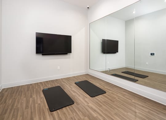 a yoga room with four yoga mats and a television on the wall