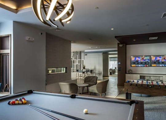 a room with a pool table and two televisions