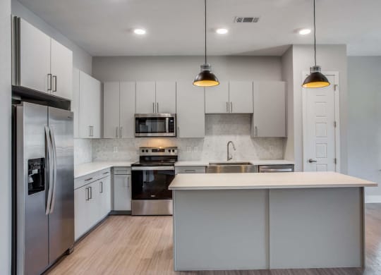 a kitchen with white cabinets and stainless steel appliances at Trailhead, Austin