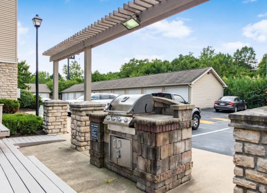 a covered patio with a grill and a parking lot