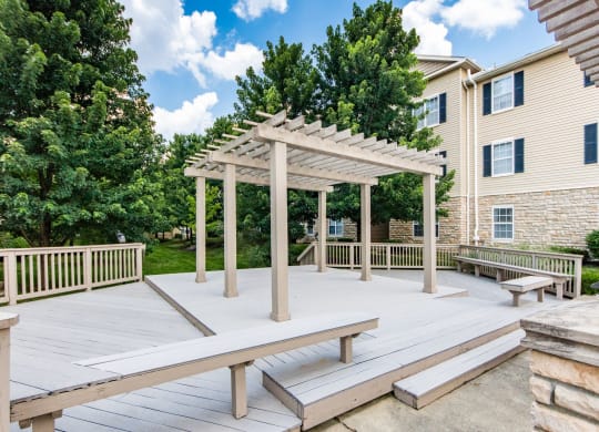 a picnic area with benches and a pergola on a deck