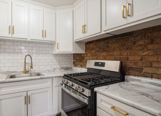 a kitchen with white cabinets and a brick wall