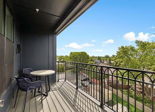 A balcony with a table and chairs overlooking a street.