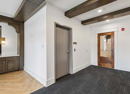 A hallway with a wooden floor and a white wall.