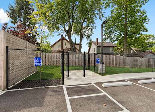 A parking lot with a black fence and a blue sign with a white wheelchair symbol.