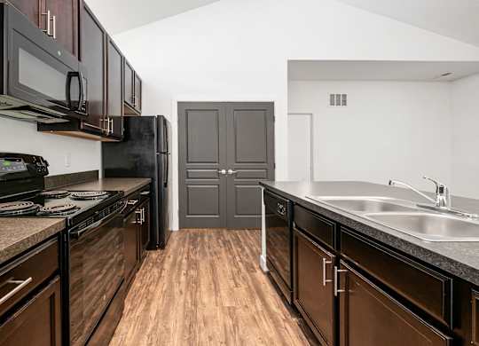 A kitchen with dark wood cabinets and a black stove top oven. at River View at Bexley Apartments, River View at Bexley 43209