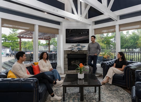 Four people sitting on a black couch in a white room.
