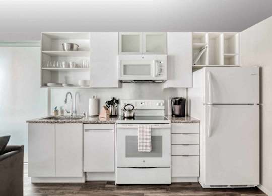 A white kitchen with a refrigerator, oven, and microwave.at Sky Central, Cincinnati, OH 45202